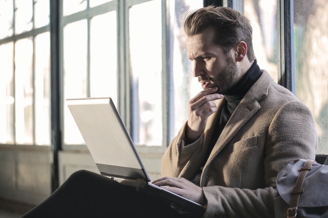 man-wearing-brown-jacket-and-using-laptop