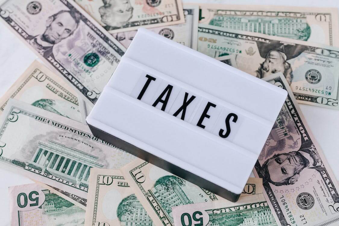 quote board with the word taxes on top of USD bills