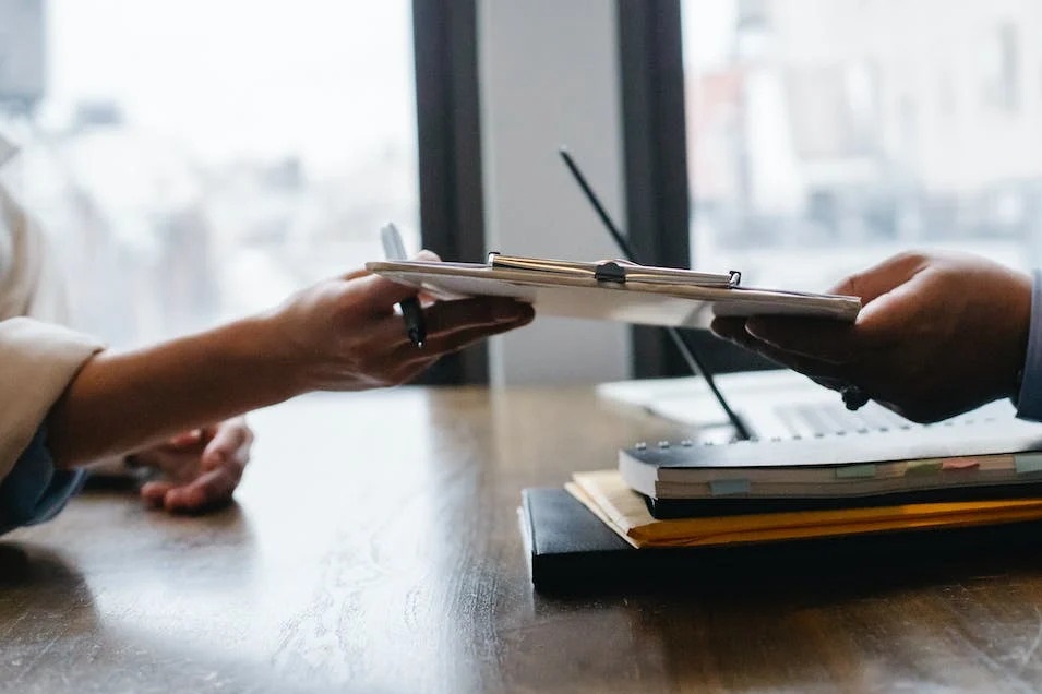 two people exchanging clip board with tax forms